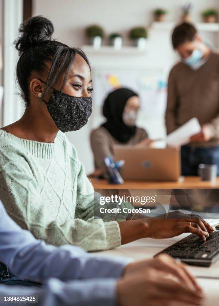 multi-ethnic team in office working with face masks on faces - employee engagement mask stock pictures, royalty-free photos & images