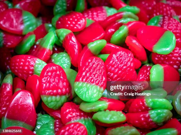 close up macro shot of children's sweets and confectionary. fizzy sweet and sour sugar coated strawberry jelly shapes - tum tum stockfoto's en -beelden