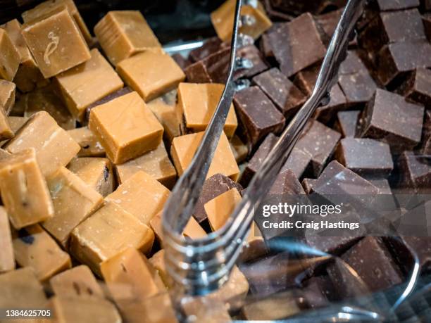 macro close up of luxury delicious milk and white chocolate fudge confectionary squares  with self serve scoop filling the full frame. sweets and candy - fudge stock pictures, royalty-free photos & images