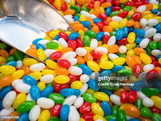 close up macro shot of children's sweets and confectionary. multi coloured pile of traditional jelly beans with self serve scoop - jellybean stock pictures, royalty-free photos & images