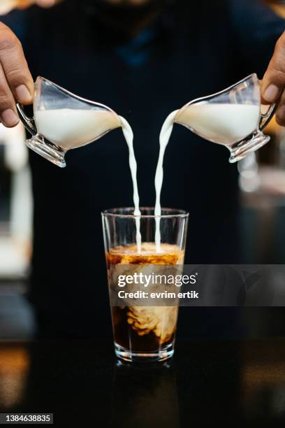 mann gießt milch in eiskaffee - pouring softdrink stock-fotos und bilder