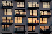 The evening sun is reflected in the modern glass facade with balconies