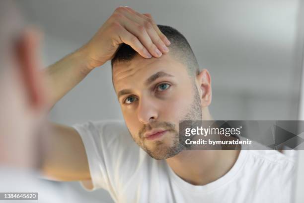 man checking face in mirror - human skin stock pictures, royalty-free photos & images