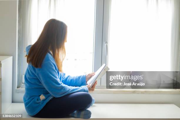 woman reading a book by the window - pessoas notebook stock pictures, royalty-free photos & images