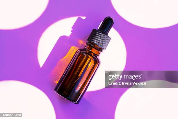 close-up  cosmetics product bottle  with face serum or essential oil with oxygen aqua bubbles on a purple  color background with circles. color of the year 2022  purple violet very peri. - korean beauty products foto e immagini stock