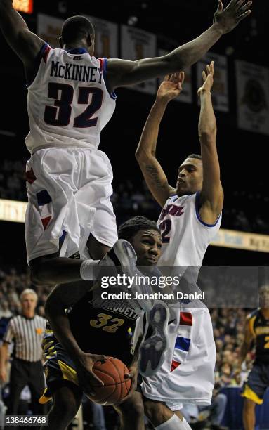 Jae Crowder of the Marquette Golden Eagles waits to shoot as Charles McKinney of the DePaul Blue Demons leap past and Cleveland Melvin defends at...