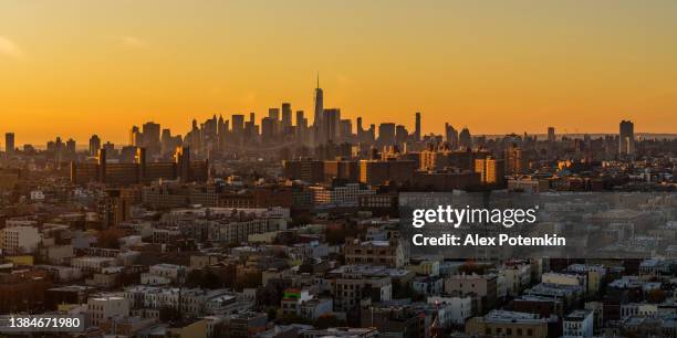 downtown manhattan and freedom tower are illuminated by sunset, silhouetted against the colorful sky. the distant view across brooklyn's residential area on the sunset. extra-large, high-resolution stitched panorama. - affordable housing stock pictures, royalty-free photos & images
