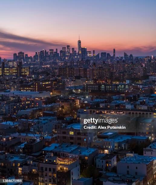 distrito residencial en bushwick, brooklyn, nueva york, con la vista lejana de la torre de la libertad en el bajo manhattan, iluminada por las luces de la calle de la ciudad. panorama vertical cosido de alta resolución. - viviendas asequibles fotografías e imágenes de stock