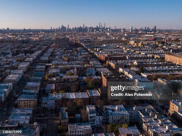 residential district in bushwick, brooklyn, new york, in the sunny day, with the remote midtown manhattan skyline in the backdrop. - brooklyn new york houses aerial stock pictures, royalty-free photos & images