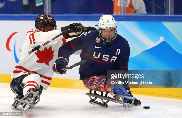 Declan Farmer of Team United States controls the puck against Garrett Riley of Team Canada in the third period during the Para Ice Hockey Gold Medal...