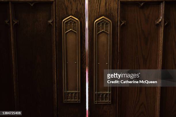 wooden doors that open to center aisle in church with gold detail - heritage hall stock pictures, royalty-free photos & images
