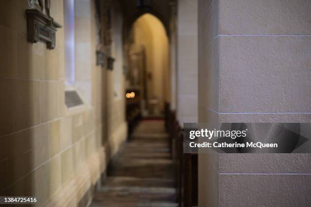 side aisle corridor in church with distant view of traditional prayer candles - messe gottesdienst stock-fotos und bilder