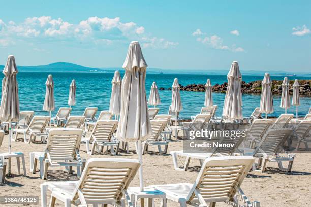 empty sunbeds and umbrellas on the pomorie beach - pomorie fotografías e imágenes de stock