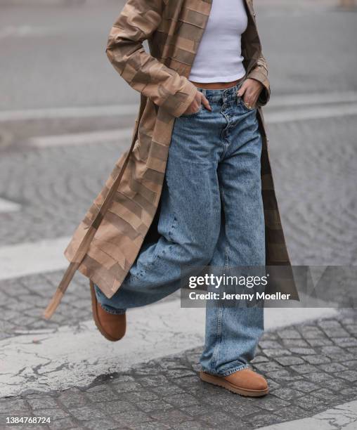 Alexandra Guerain wearing a beige long coat with pattern, a white top, blue jeans and UGG chestnut Classic Mini II Boot on March 04, 2022 in Paris,...