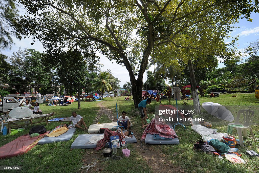 Patients rest under the trees outside a