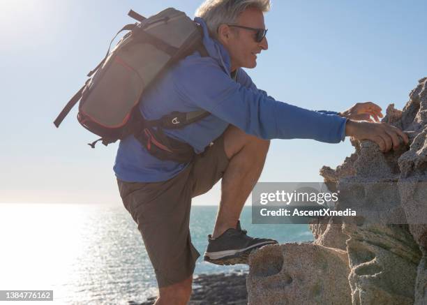 hiker scrambles up cliff over the pacific ocean - scrambling bildbanksfoton och bilder