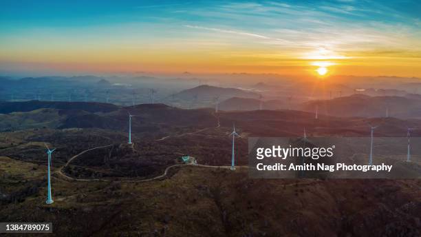 sunrise over grassy hills, with windmills all around - renewable energy india stock pictures, royalty-free photos & images