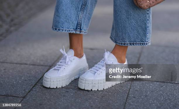 Cathy Hummels wearing Zara blue wide leg denim, Maison Valentino Rockstud beige bag and Prada white and sparkling sneaker on March 11, 2022 in...