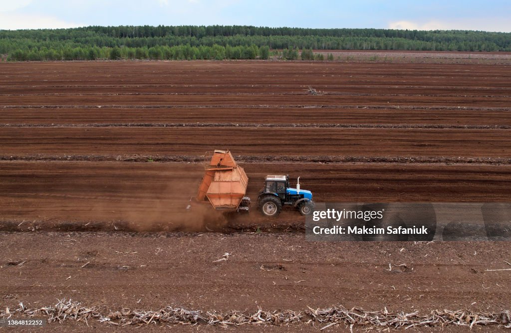 Peat Harvester Tractor on Collecting Extracting Peat. Mining and harvesting peatland. Area drained of the mire are used for peat extraction. Drainage and destruction of peat bogs.