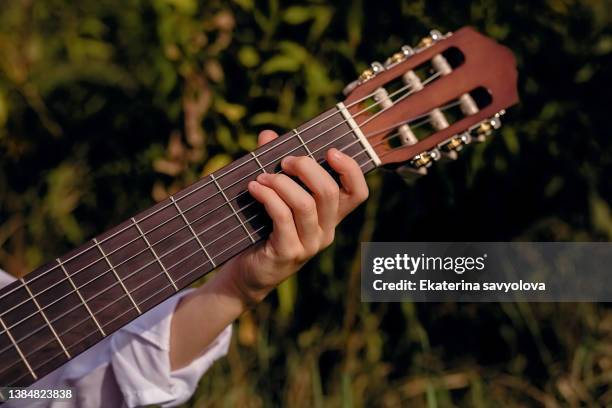 a boy with a guitar on a sunny day in a field with grass. - autor de canciones fotografías e imágenes de stock