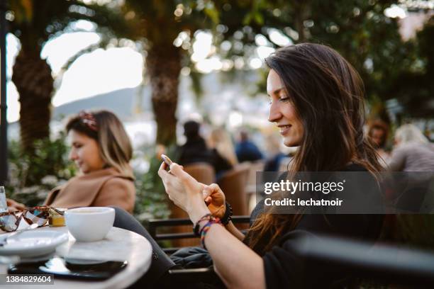 women relaxing and texting in the beach cafe - cafe at beach bildbanksfoton och bilder
