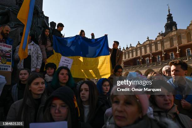 Ukrainians, Belarusians and Poles hold banners and flags as they demand NATO enforce a no-fly zone in Ukraine during a protest at Krakow's UNESCO...