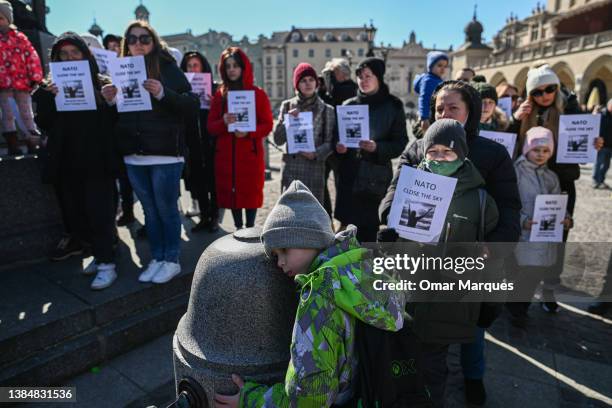 Ukrainians, Belarusians and Poles hold banners and flags as they demand NATO enforce a no-fly zone in Ukraine during a protest at Krakow's UNESCO...