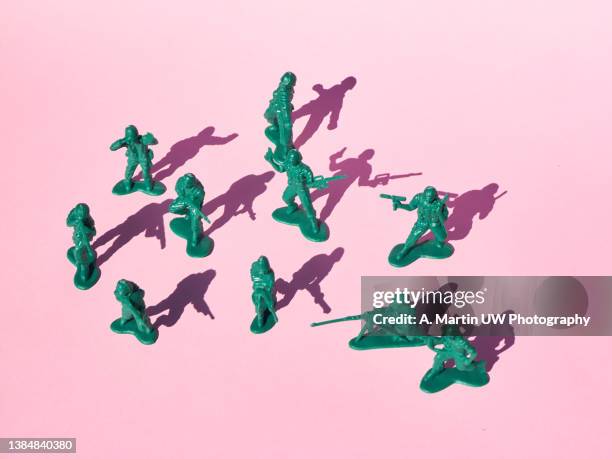 group of plastic toy soldiers pointing guns at each other on a cloured background - military camouflage stock pictures, royalty-free photos & images