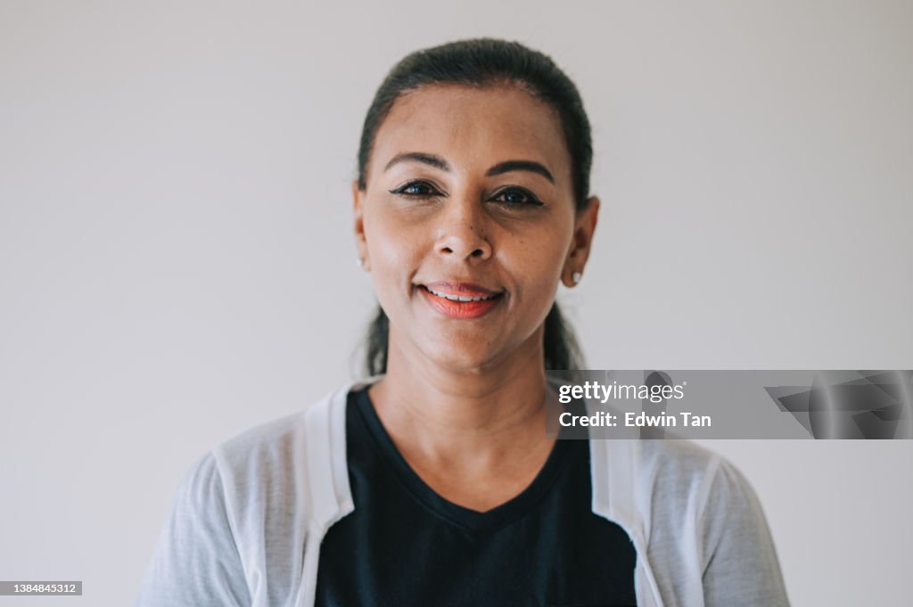 Portrait headshot Asian Indian mature woman smiling looking at camera with white background