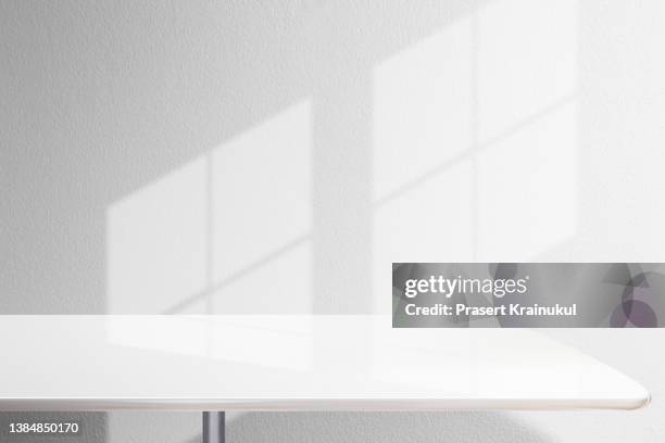 shadow on a white concrete walls on table. - tavolo foto e immagini stock