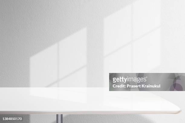 shadow on a white concrete walls on table. - table stock pictures, royalty-free photos & images