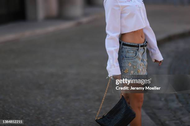 Camila Mendes seen wearing gold earrings, a white flower embroidered cropped shirt from Miu Miu, a blue denim short skirt with flower details, a...