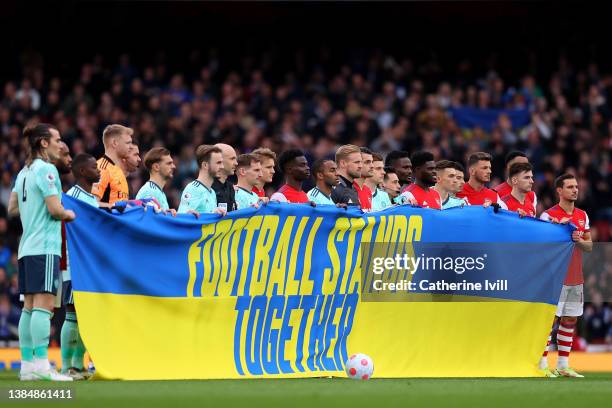 Arsenal and Leicester City fans hold a Ukraine flag reading 'Football Stands Together' to indicate peace and sympathy with Ukraine prior to the...