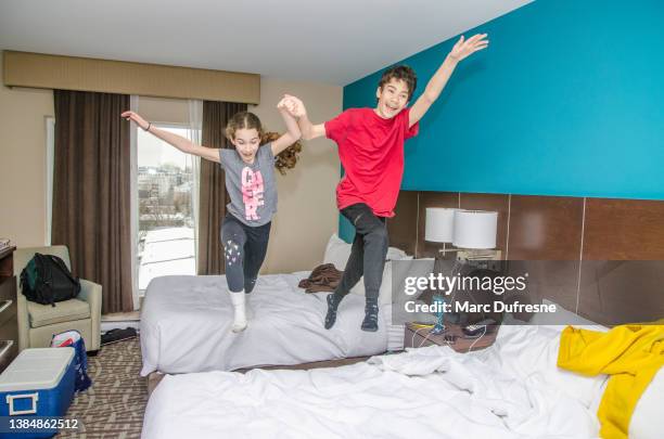 two kids jumping on beds in hotel room - a boy jumping on a bed stock pictures, royalty-free photos & images