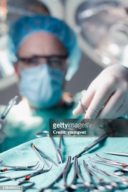 cirujano que alcanza el conductor de la aguja y la sutura durante la cirugía - suture fotografías e imágenes de stock