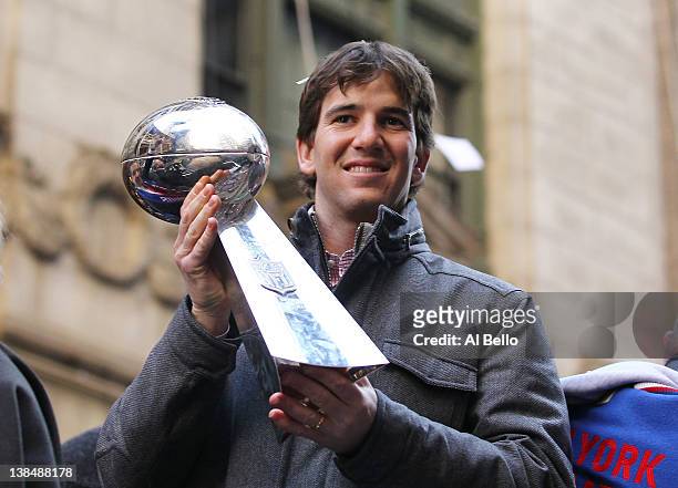 Eli Manning of the New York Giants holds the Vince Lombardi Trophy during the New York Giants' ticker tape victory parade down the Canyon of Heros on...