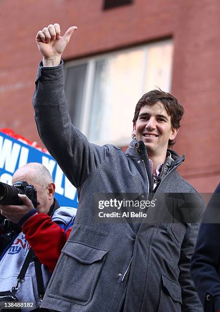 Eli Manning of the New York Giants gives a thumbs up to the crowd during the New York Giants' ticker tape victory parade down the Canyon of Heros on...