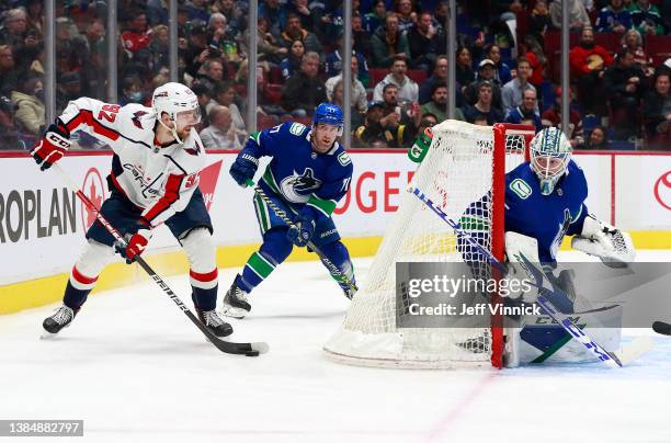 Thatcher Demko and Brad Hunt of the Vancouver Canucks look on as Evgeny Kuznetsov of the Washington Capitals skates with the puck during their NHL...