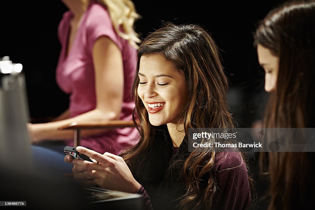 Model backstage at fashion show looking at phone