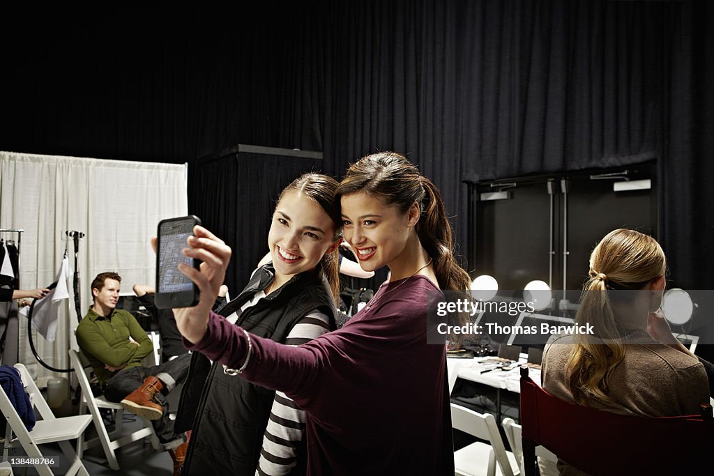 Two models backstage at fashion show taking photo