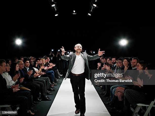 designer receiving applause and waving to crowd - fashionshows stockfoto's en -beelden