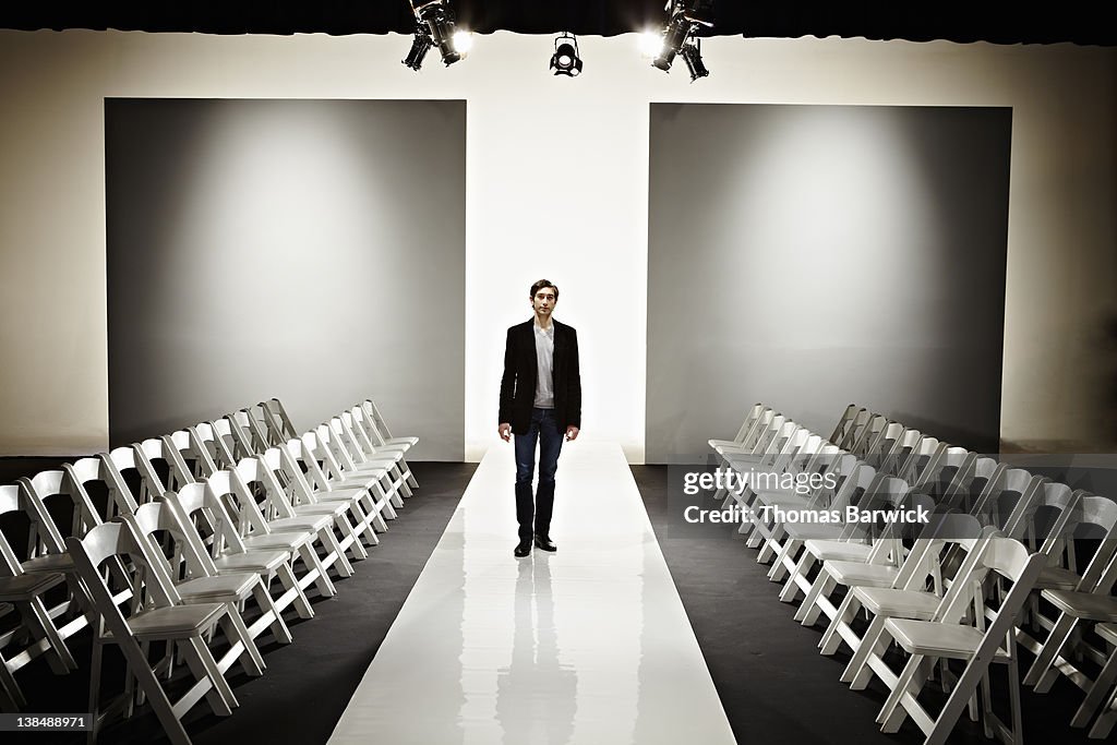 Young fashion designer standing on empty catwalk