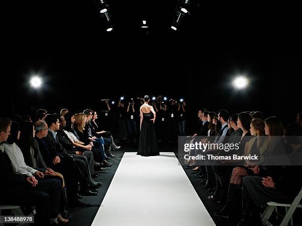 model in gown at end of catwalk posing - catwalk runway stock pictures, royalty-free photos & images