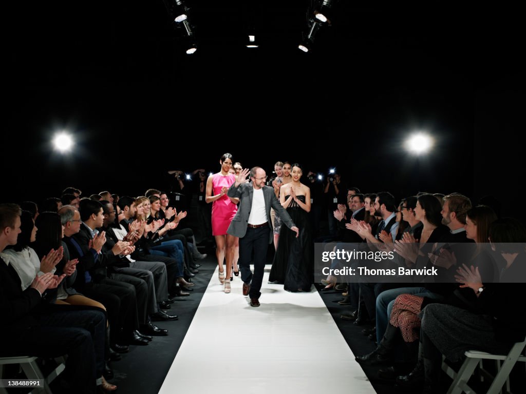 Designer and models walking down catwalk