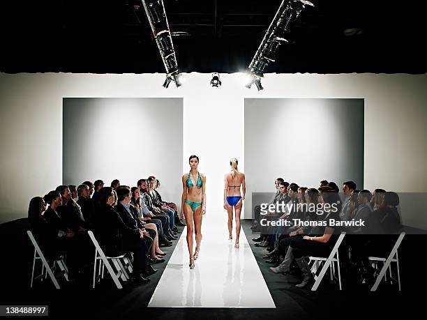 two models in swimsuits walking down catwalk - fashion show stockfoto's en -beelden