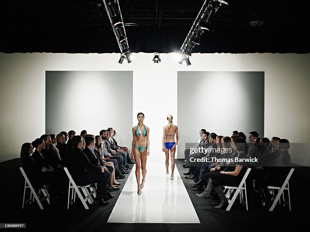 Two models in swimsuits walking down catwalk