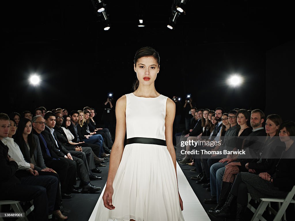 Model walking in foreground on catwalk