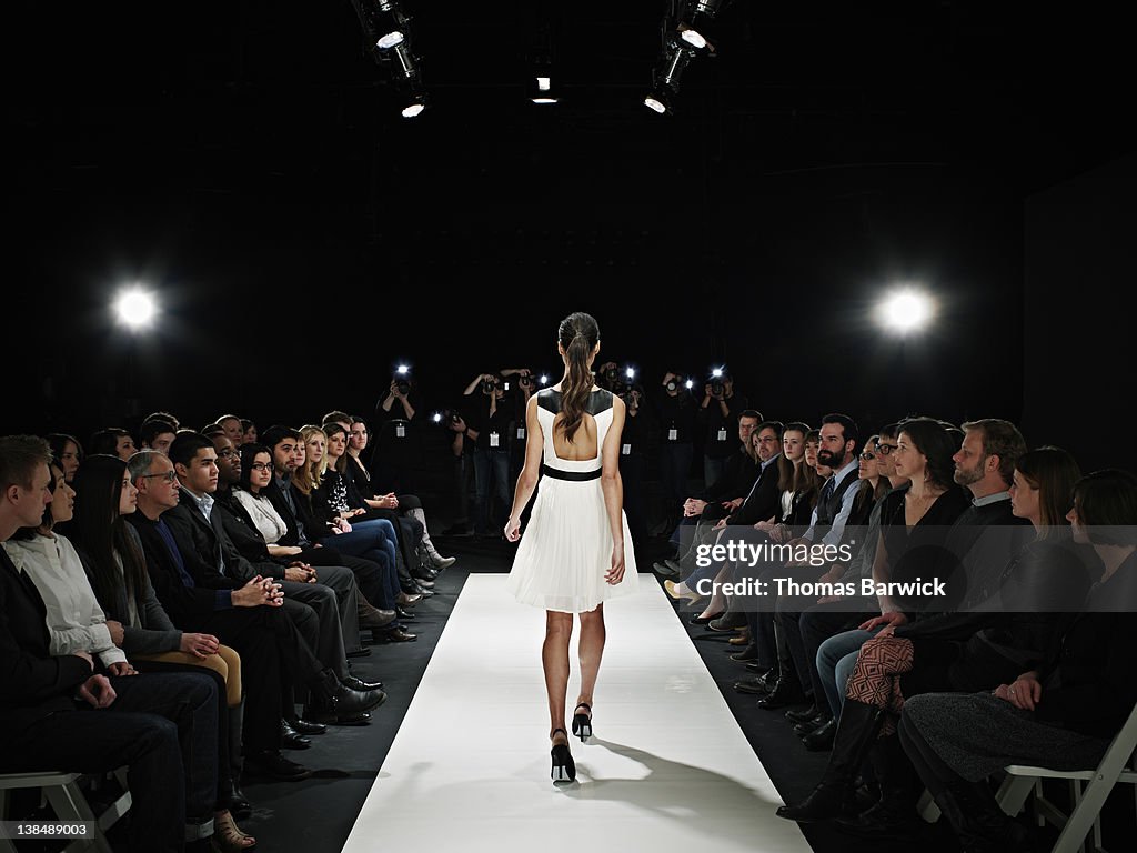 Model walking down catwalk during fashion show