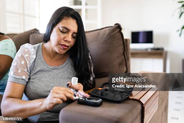woman checking blood sugar level at home - diabetic stockfoto's en -beelden