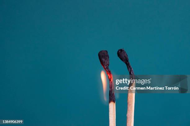 close-up of two burning matchsticks on green background. - couple dark background stock-fotos und bilder